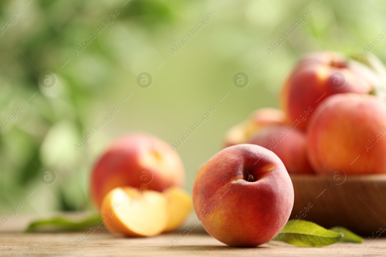 Photo of Fresh sweet peaches on wooden table outdoors