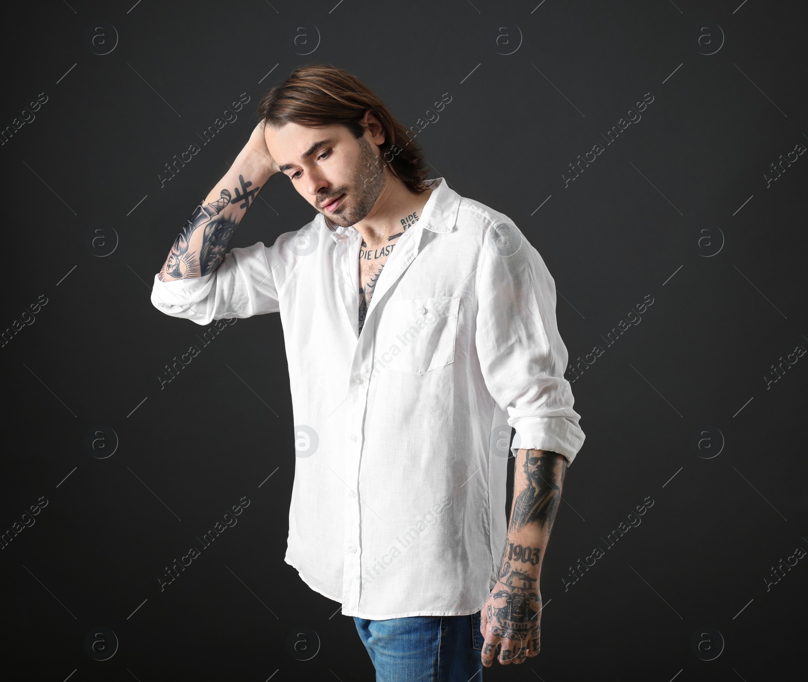 Photo of Young man with tattoos on body against black background