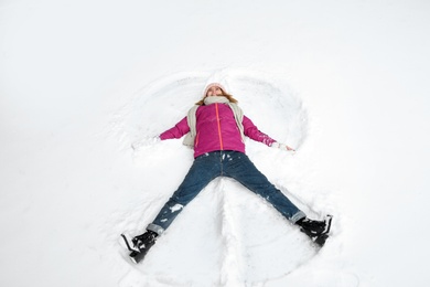 Beautiful woman making snow angel on winter day