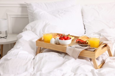 Photo of Good morning. Tray with tasty breakfast on bed at home