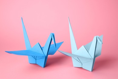 Photo of Origami art. Handmade paper cranes on pink background