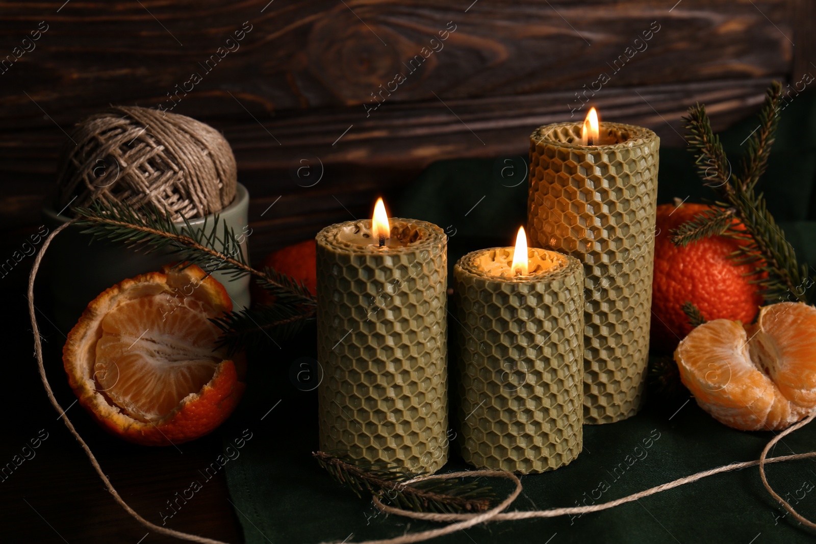 Photo of Beautiful burning beeswax candles, rope and tangerines on table