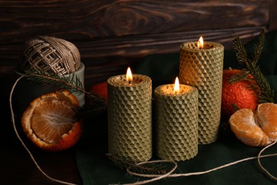 Beautiful burning beeswax candles, rope and tangerines on table