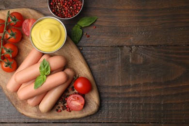 Delicious boiled sausages, sauce, tomatoes and spices on wooden table, flat lay. Space for text