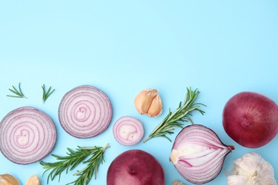 Fresh red onions, garlic and rosemary on light blue background, flat lay. Space for text