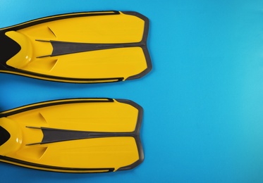 Pair of yellow flippers on color background, top view with space for text
