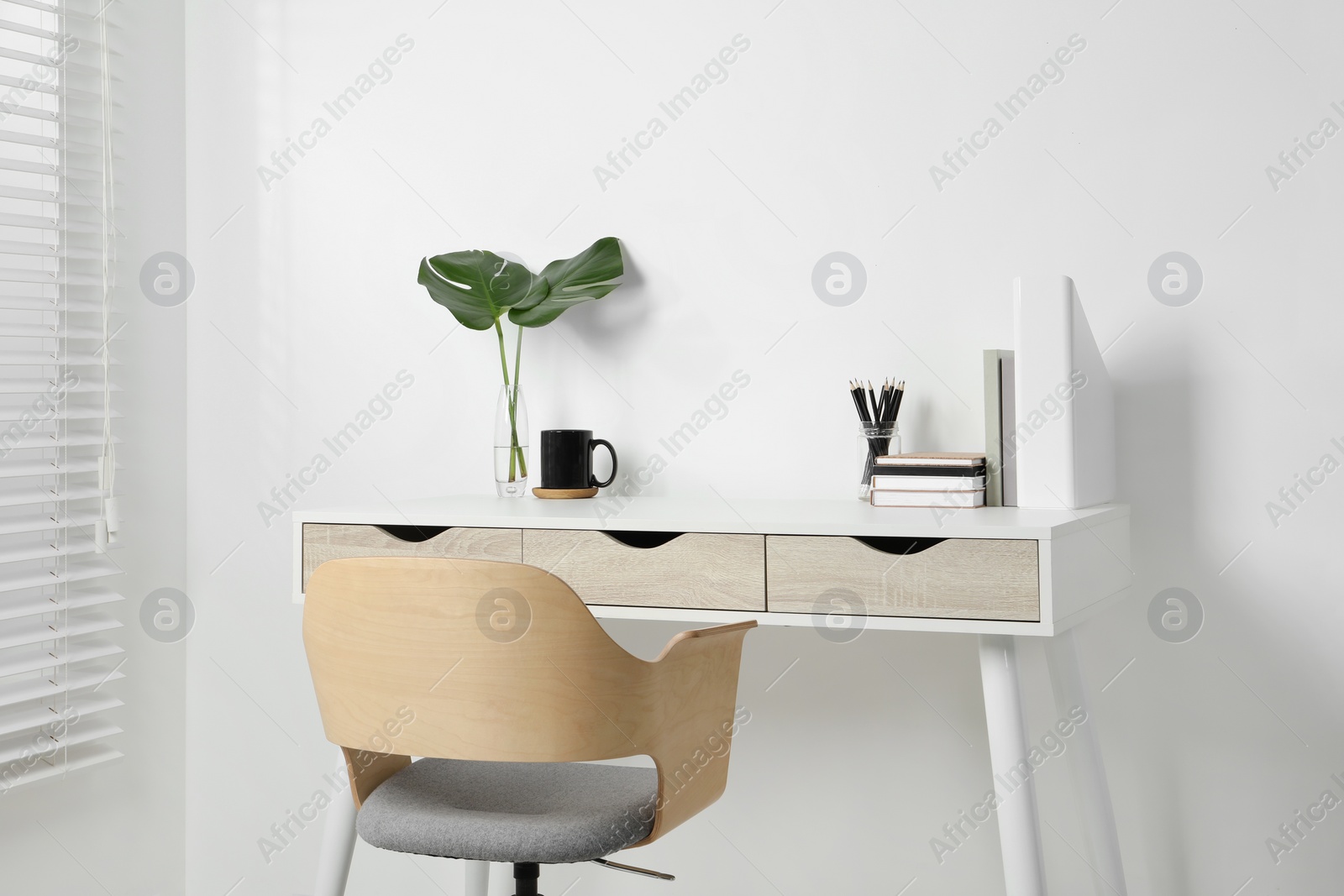 Photo of Comfortable workplace with white desk near wall indoors