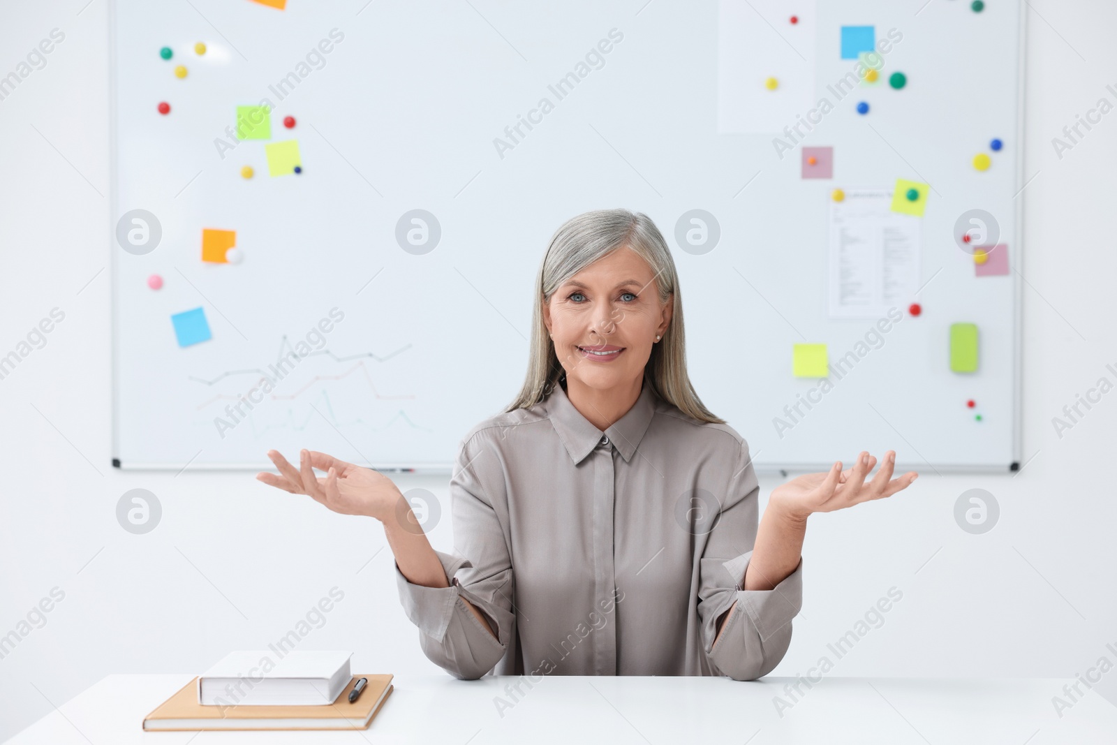 Photo of Happy professor giving lecture at desk in classroom