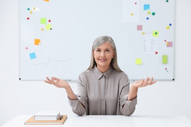 Happy professor giving lecture at desk in classroom