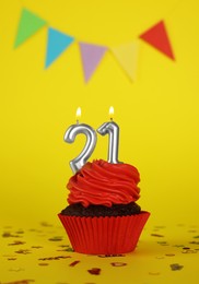 Photo of Delicious cupcake with number shaped candles on yellow background. Coming of age party - 21th birthday