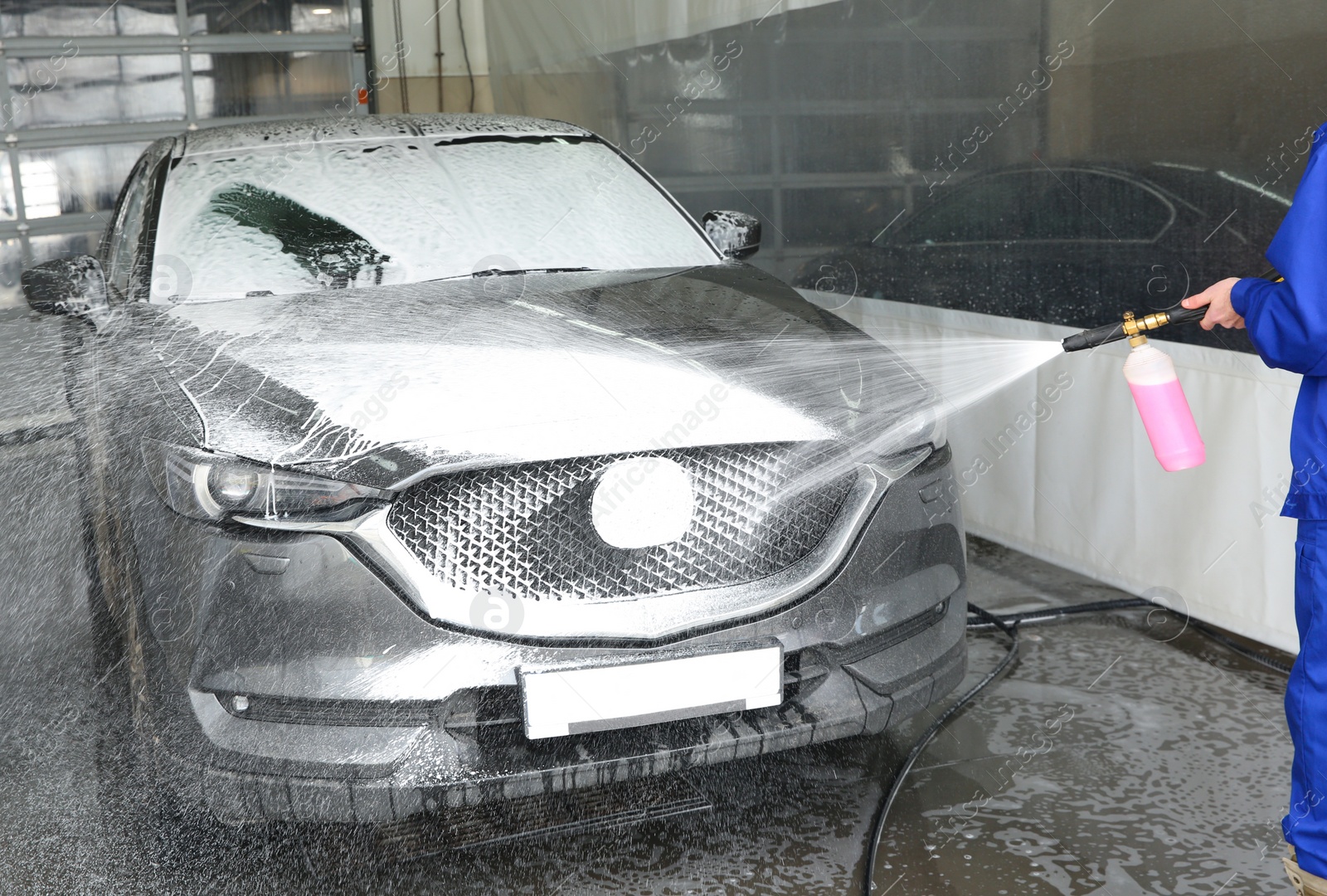 Photo of Worker cleaning automobile with high pressure water jet at car wash