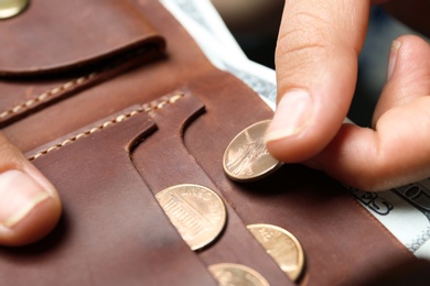 Photo of Young woman putting coin into wallet, closeup