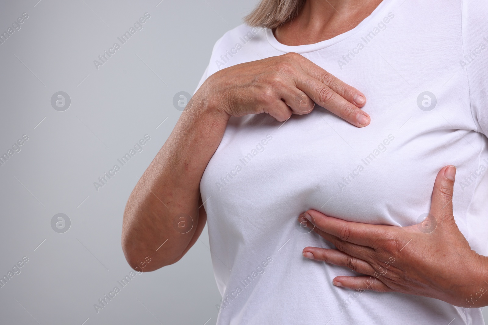 Photo of Woman doing breast self-examination on light grey background, closeup. Space for text