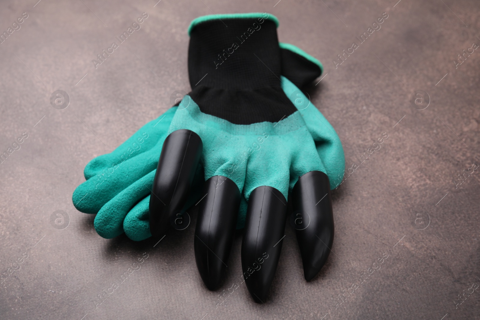 Photo of Pair of claw gardening gloves on brown textured table