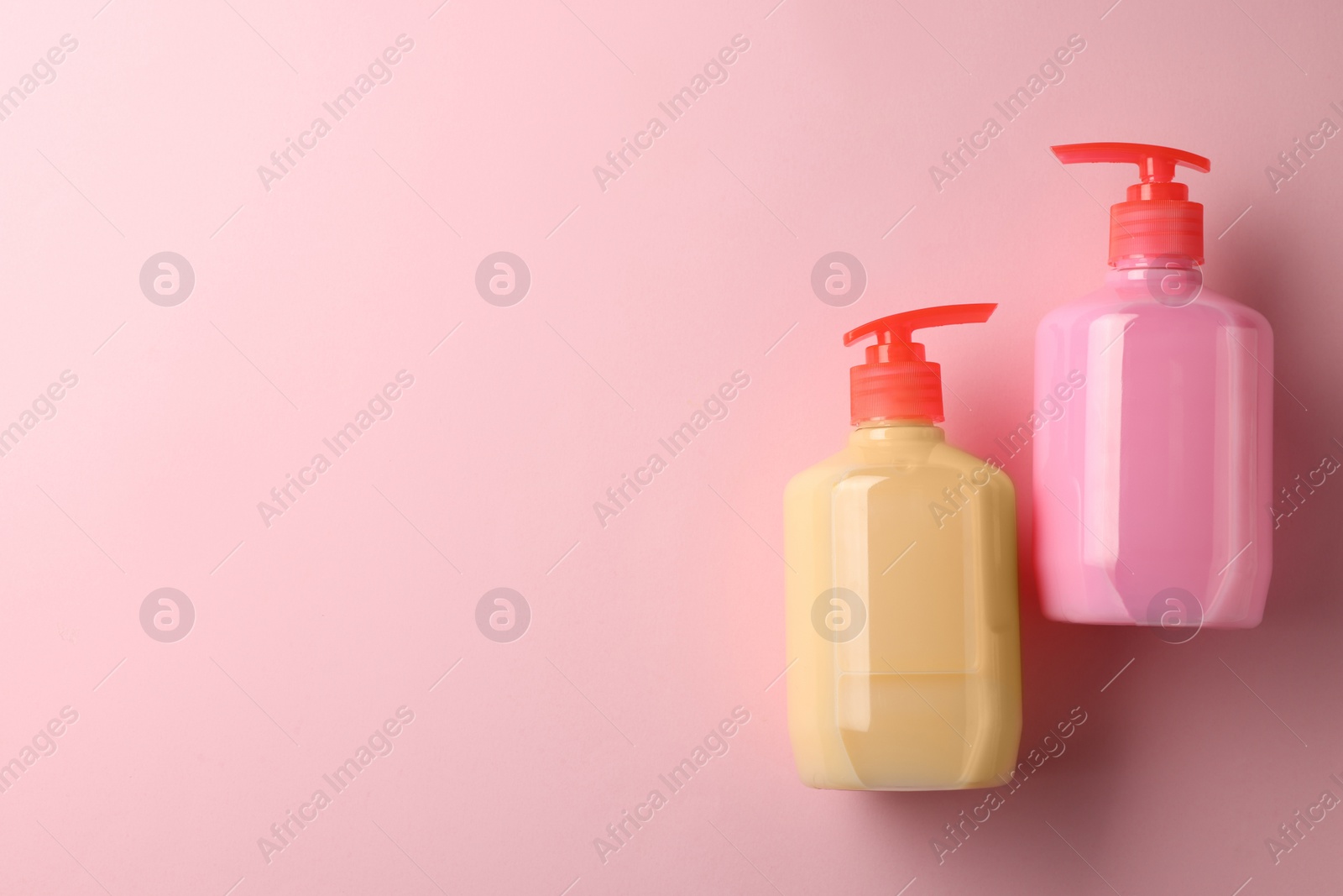 Photo of Bottles of liquid soap on pink background, flat lay. Space for text