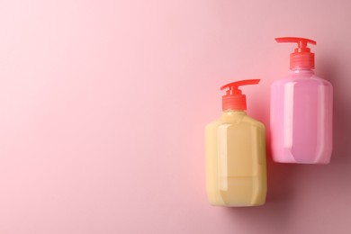Bottles of liquid soap on pink background, flat lay. Space for text