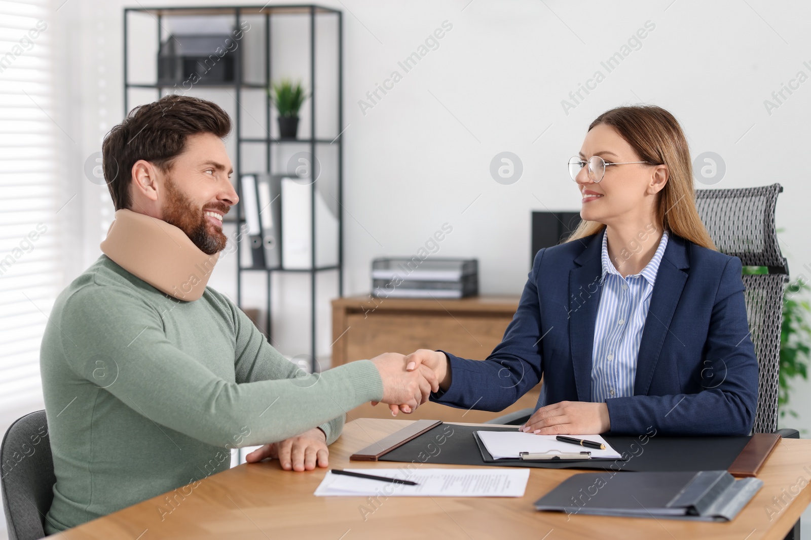 Photo of Lawyer shaking hands with injured client in office