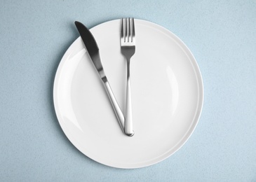 Photo of Empty plate and cutlery on light blue table, flat lay. Diet regime