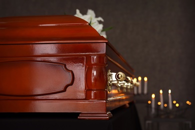 Wooden casket with white lilies in funeral home, closeup