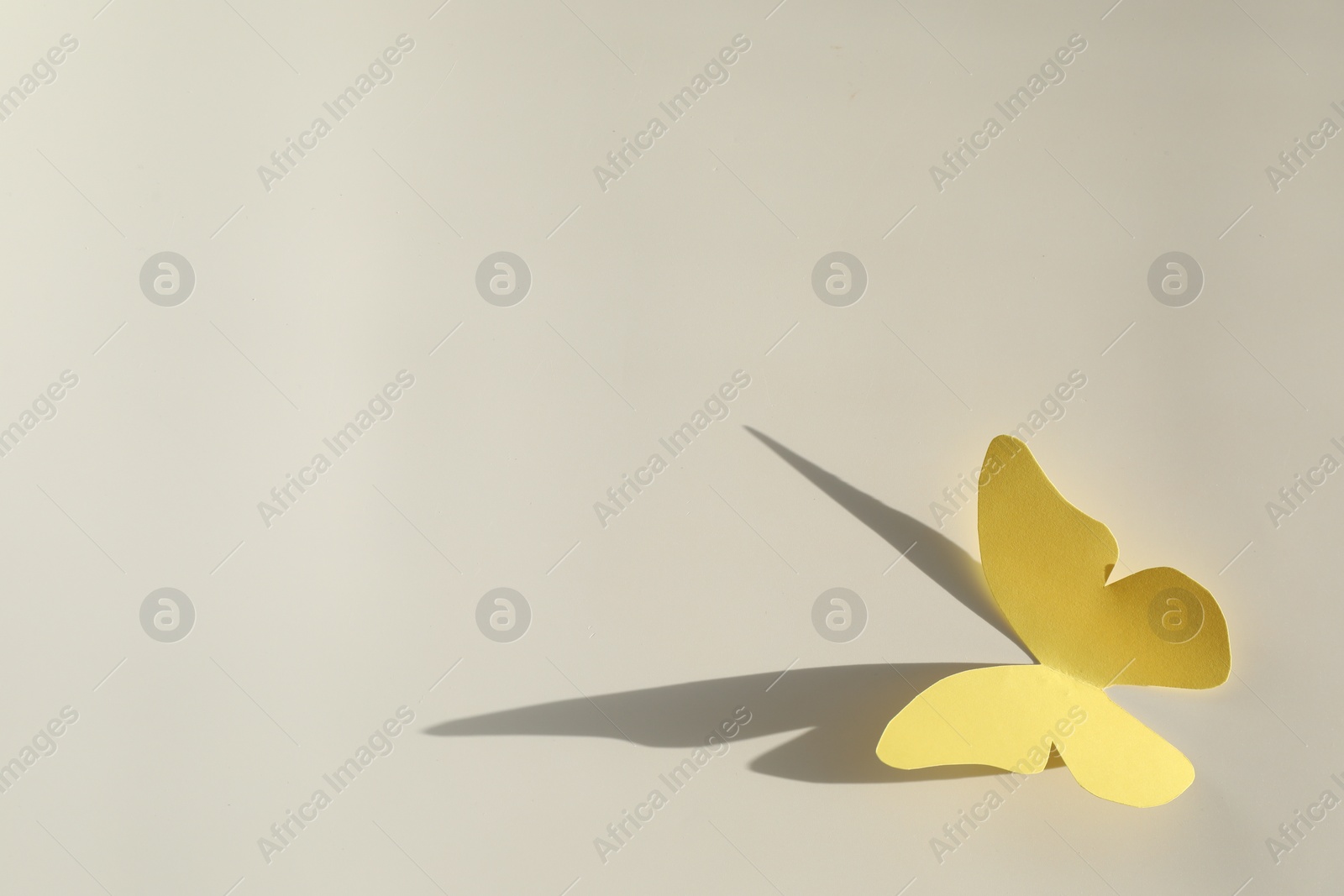 Photo of Yellow paper butterfly on light grey background, top view. Space for text