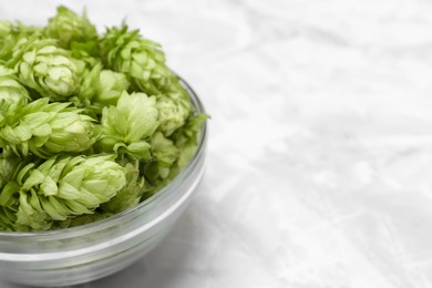 Photo of Bowl of fresh green hops on light grey marble table, closeup. Space for text