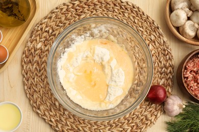 Photo of Bowl with flour, eggs and products on wooden table, flat lay