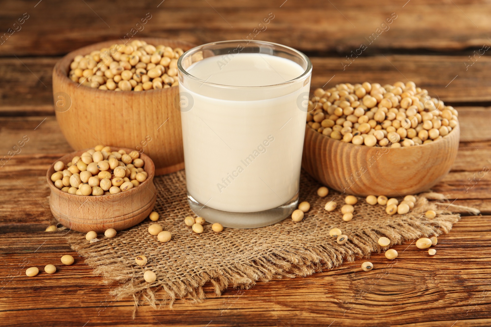 Photo of Glass with fresh soy milk and grains on wooden table