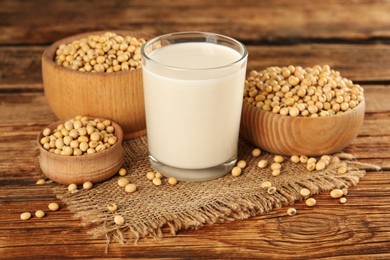 Glass with fresh soy milk and grains on wooden table