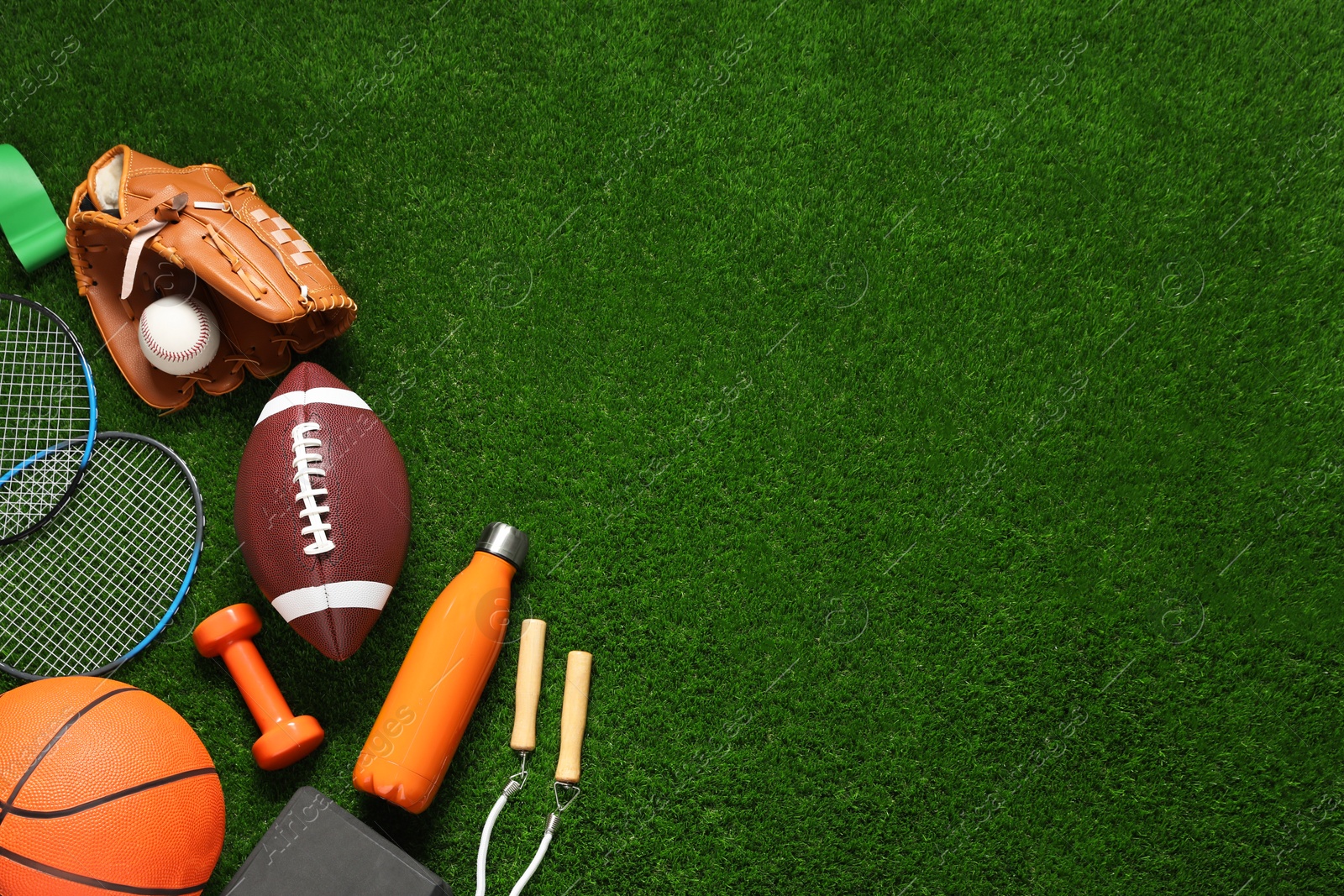 Photo of Different sports equipment on green grass, flat lay. Space for text