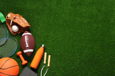 Photo of Different sports equipment on green grass, flat lay. Space for text