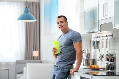 Athletic young man with protein shake in kitchen