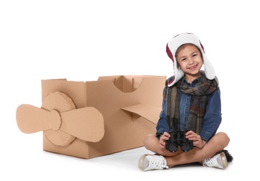 Photo of Cute little girl playing with binoculars and cardboard airplane on white background