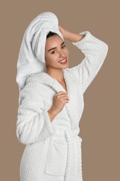 Photo of Beautiful young woman in bathrobe on brown background