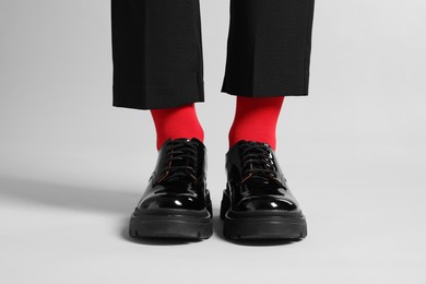 Photo of Woman in pants, shoes and stylish red socks on light grey background, closeup