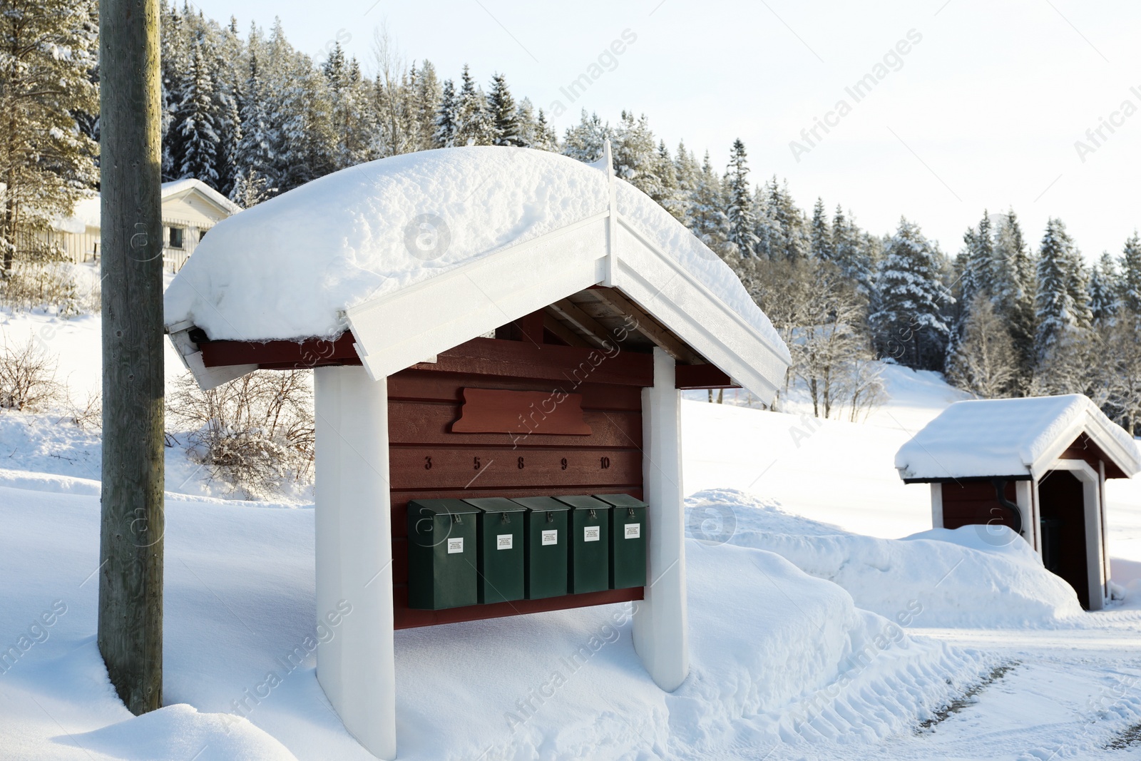 Photo of Many mailboxes under wooden roof covered with snow on winter day