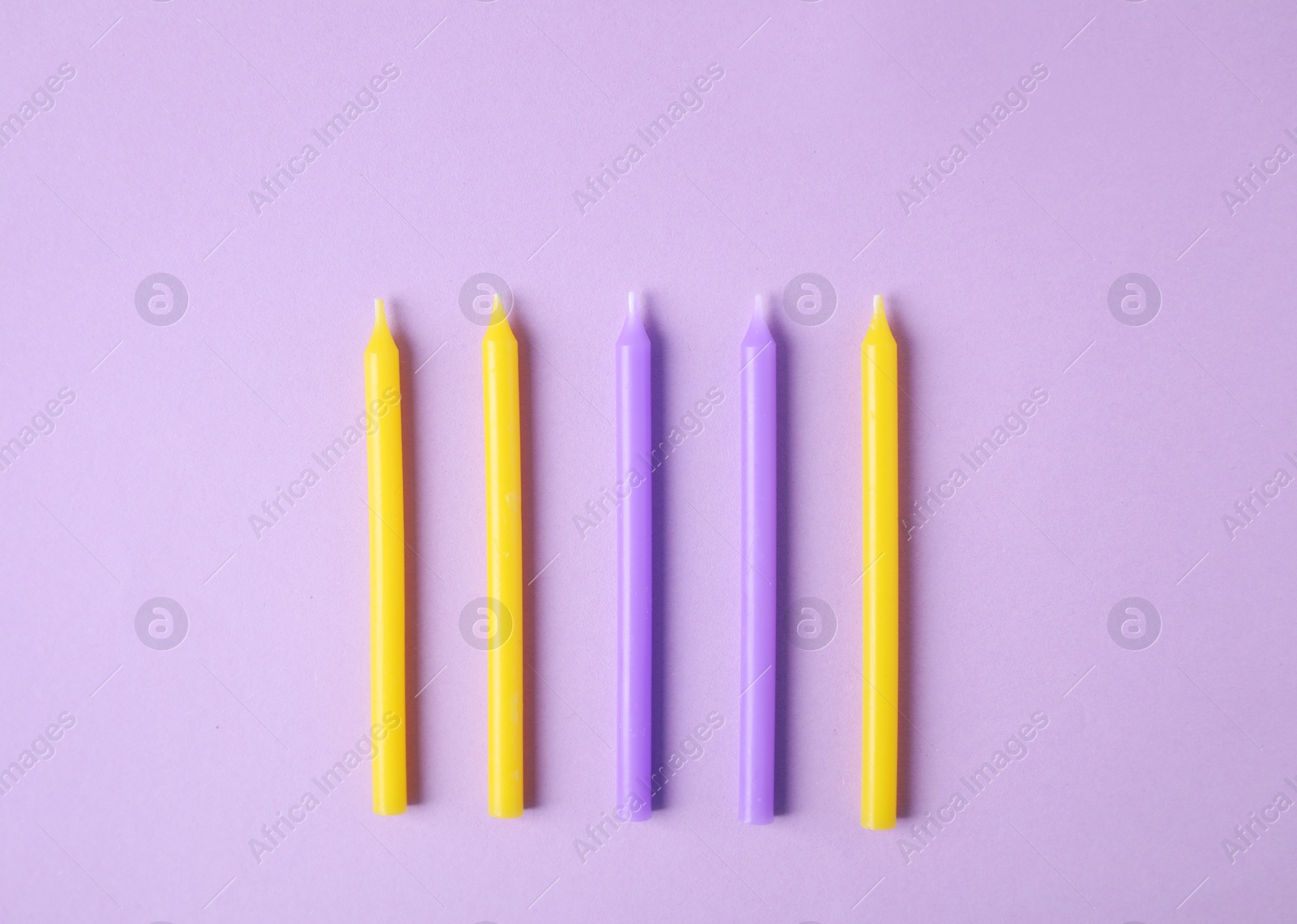 Photo of Colorful birthday candles on lilac background, flat lay