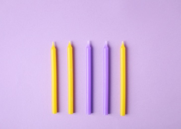 Photo of Colorful birthday candles on lilac background, flat lay