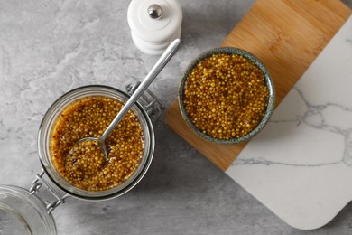Photo of Bowl and jar of delicious whole grain mustard on grey table, flat lay