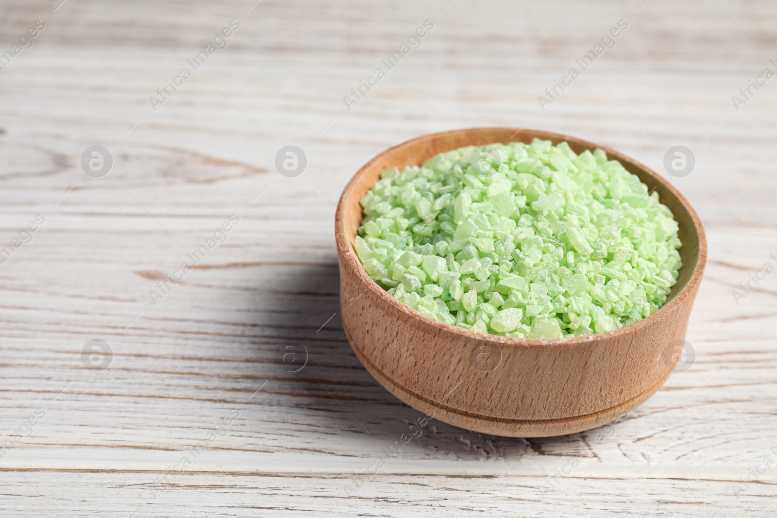 Photo of Green aromatic sea salt on white wooden table, closeup. Space for text