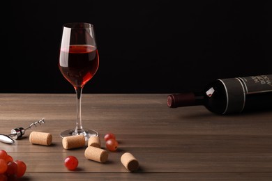 Photo of Wine, corks, grapes and corkscrew on wooden table