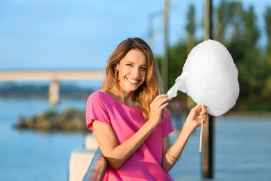 Happy young woman with cotton candy on waterfront