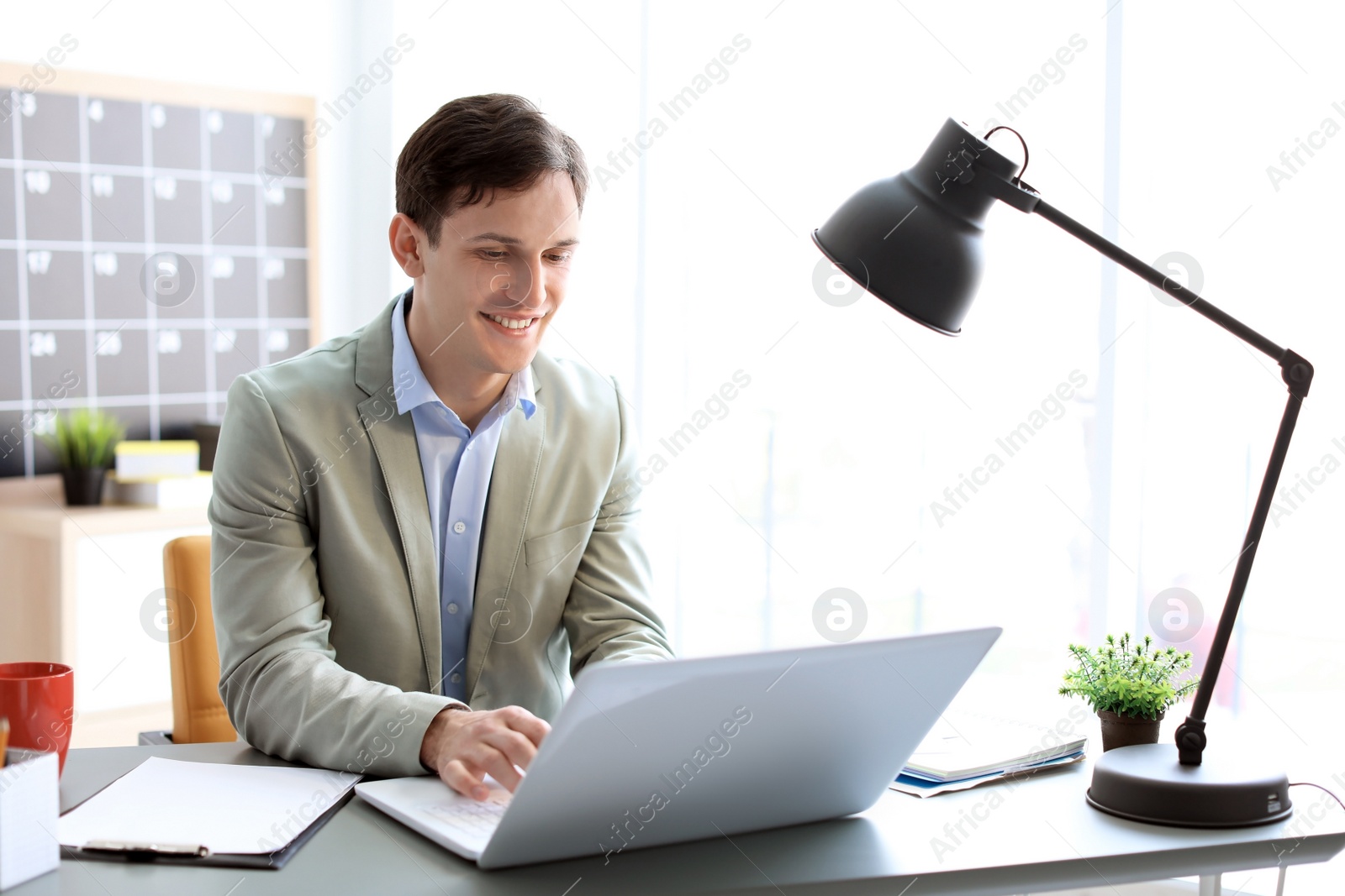 Photo of Portrait of confident young businessman with laptop at table