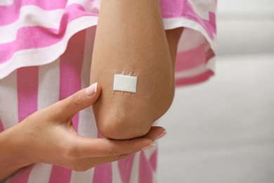 Photo of Woman with adhesive bandage on elbow against light background, closeup