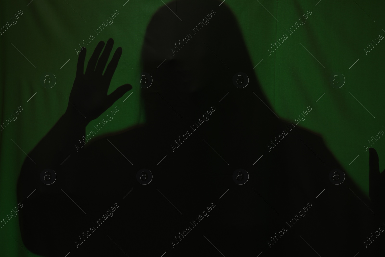 Photo of Silhouette of creepy ghost behind dark green cloth