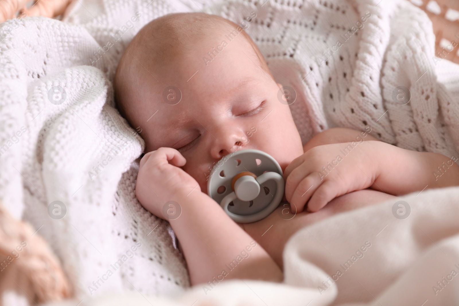 Photo of Cute newborn baby with pacifier sleeping on white blanket, closeup