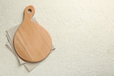 Photo of Wooden cutting board and napkin on white textured table, top view. Space for text