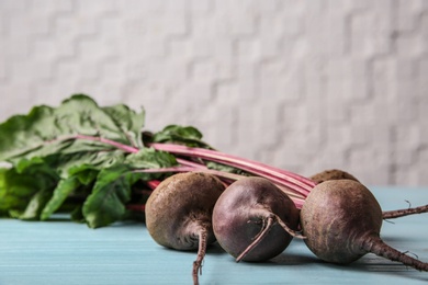 Photo of Bunch of fresh beets with leaves on blue wooden table against white background. Space for text