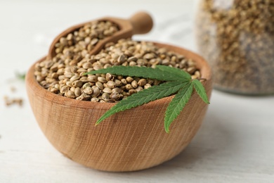 Photo of Organic hemp seeds and leaf in bowl on white table