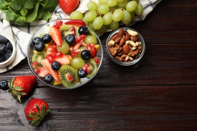 Photo of Tasty fruit salad in bowl and ingredients on wooden table, flat lay. Space for text