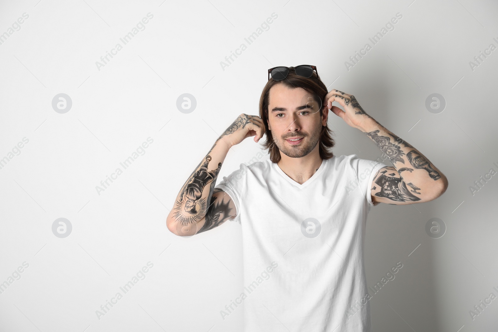 Photo of Young man with tattoos on arms against white background